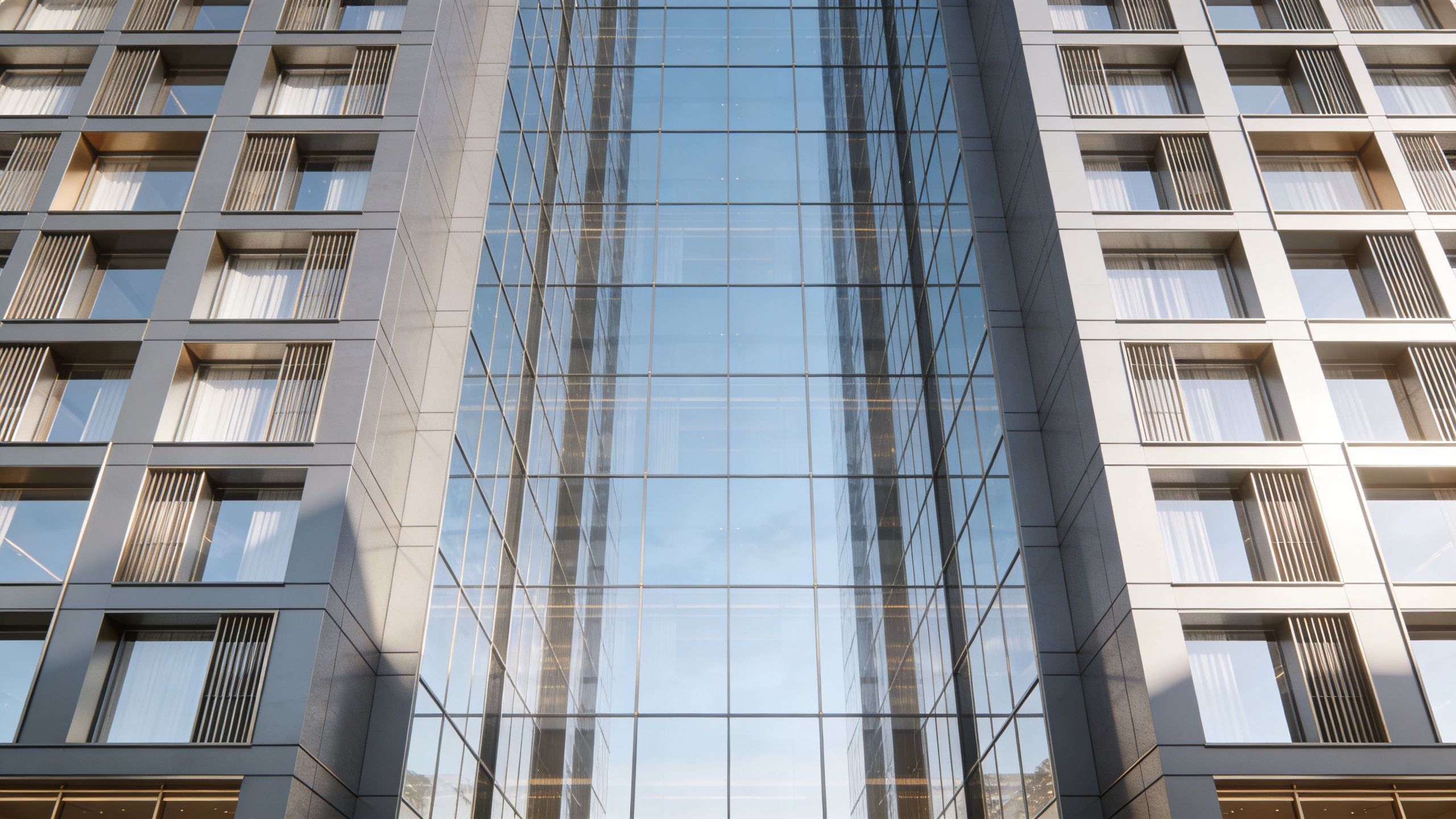 A low-angle view of a modern luxury building with glass curtain walls and geometric window patterns.