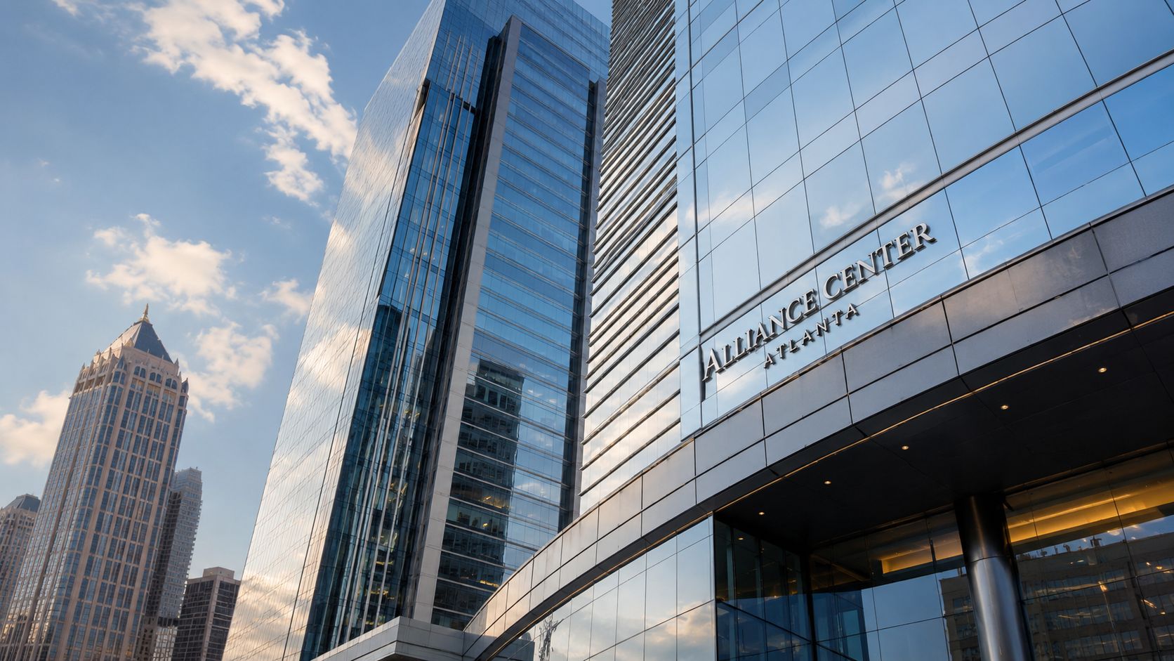 A low-angle view of the glass-clad Alliance Center building in Atlanta, Georgia, against a blue sky.
