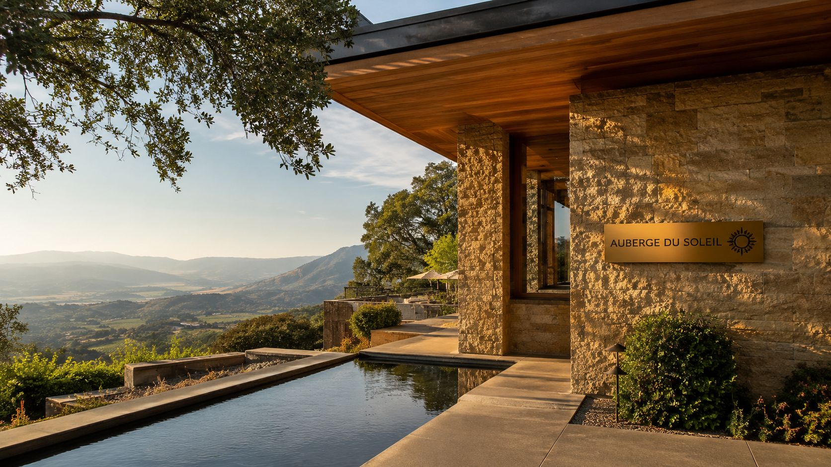 The entrance of Auberge du Soleil in Napa Valley with a reflecting pool and scenic mountain view.