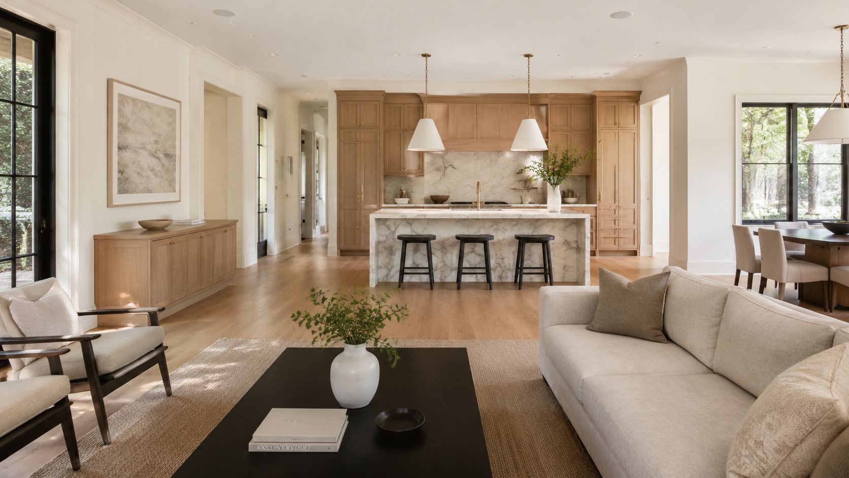 A bright and airy open-concept living space with a modern kitchen, wooden cabinetry, and neutral-toned furniture.