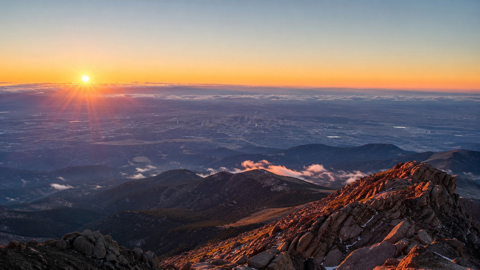 A scenic sunrise view overlooking Colorado Springs from the high rocky summit of Pikes Peak.