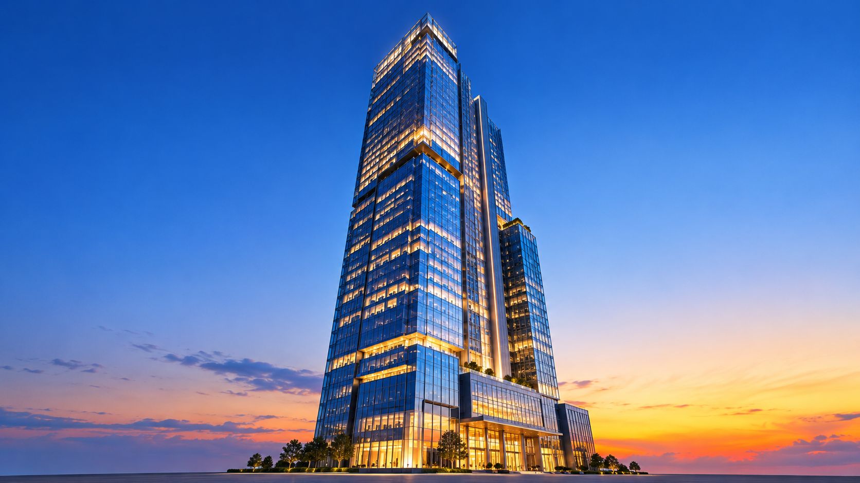 A towering glass skyscraper illuminated at dusk against a vibrant orange and blue gradient sunset sky.