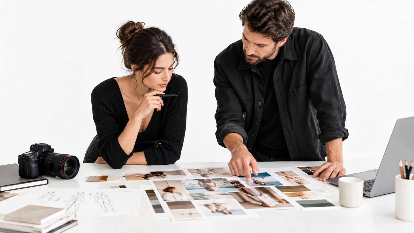 A professional man and woman working together on brand photography guidelines at a white studio desk.